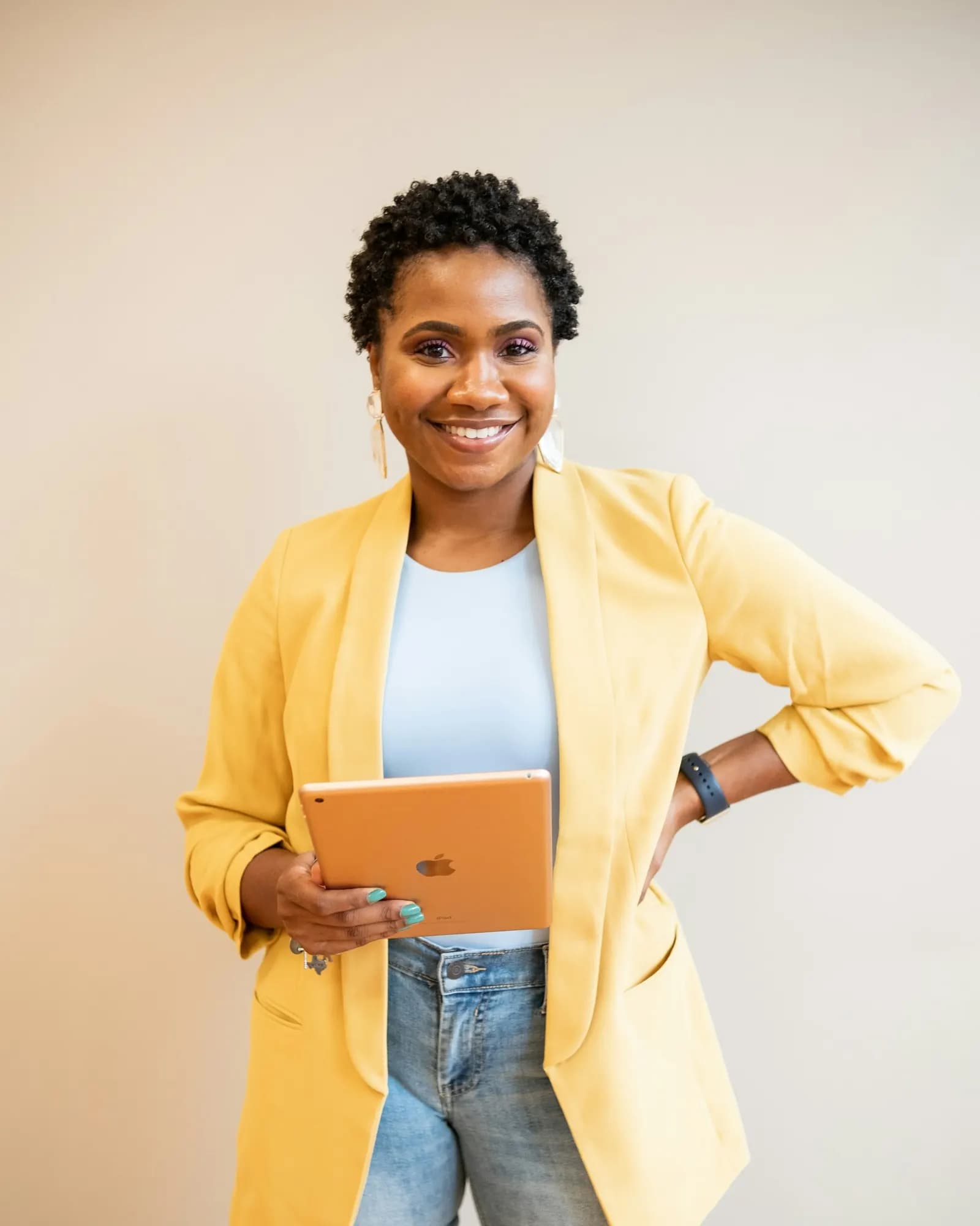 Smiling marketing strategist in a yellow blazer holding a tablet