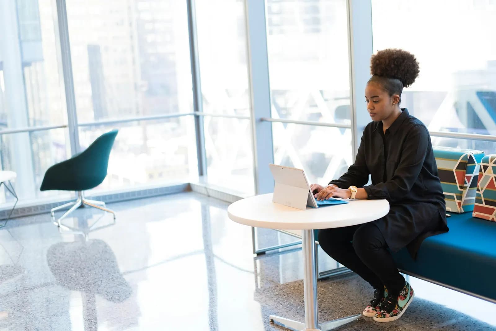 Woman working on a laptop by an office window